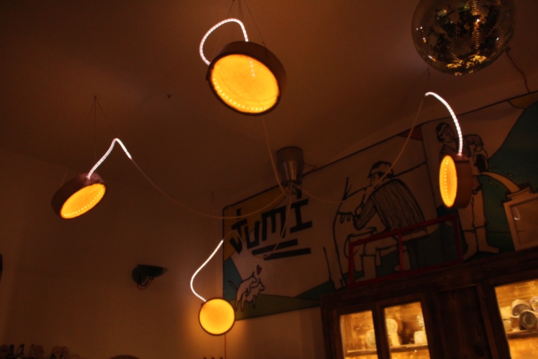 Jumi Käse Installation 2018 - Inside the store 3 Four circled shaped objects that diffuse yellow LED lights and are coming from a milk can.