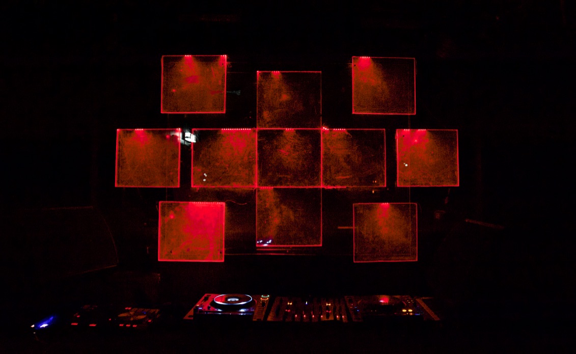 © James Morrison-Knight - Kultur For President 2019 - Acrylic glass installation A DJ booth with square-shaped acrylic glass behind it that are glowing in red colors