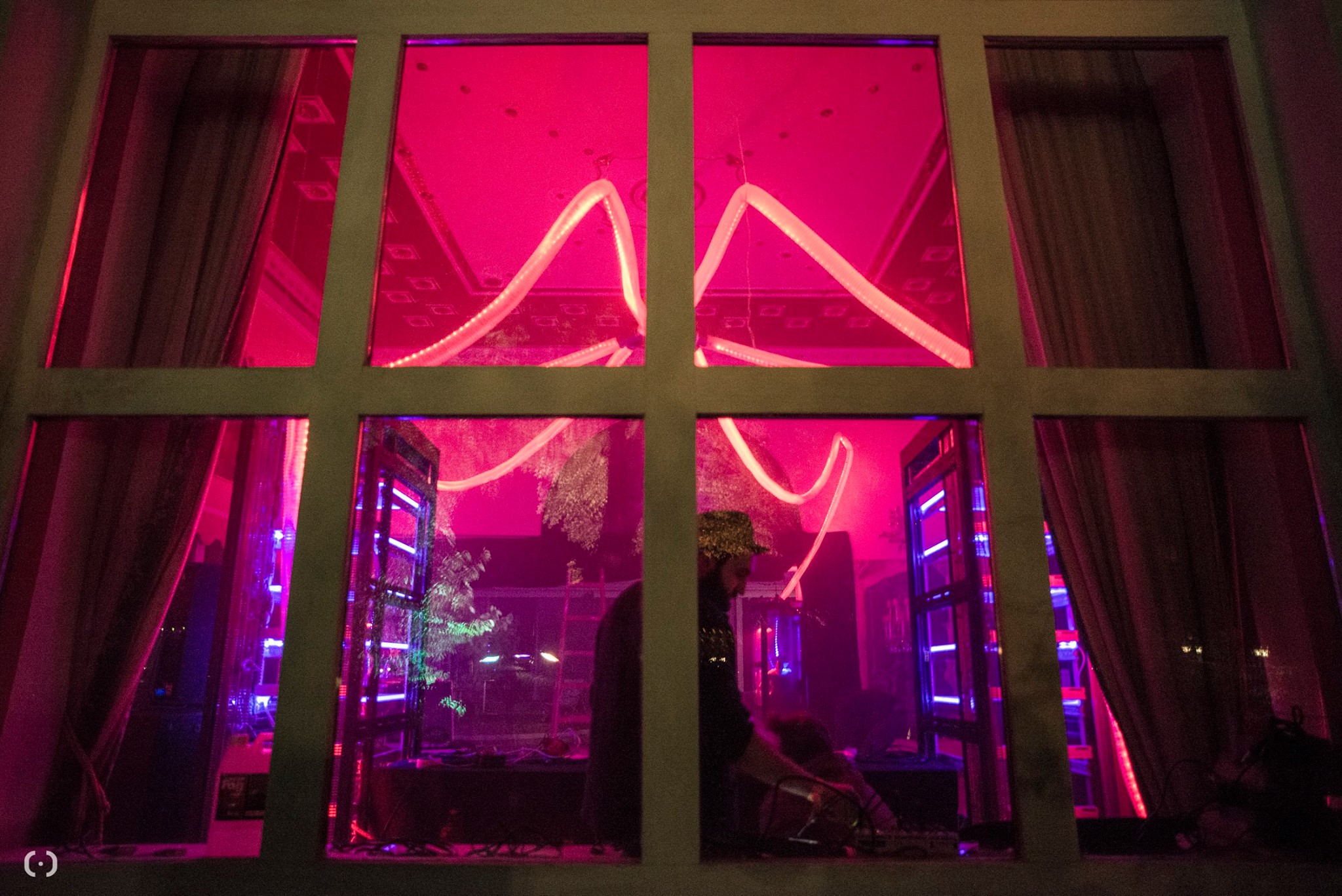 © George Kaulfersch - Tanz Durch Den Tag @ Cobenzl 2017 - Server Installation A look through a window shows a large room showing a DJ booth being between two server racks and on the ceiling there are LED hoes leading to those server racks